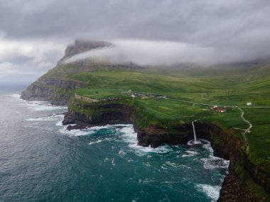 Dramatik Mulafossur şelalesi Gasadalur köyü ve arka planda kayalıklarla okyanusa dökülüyor..