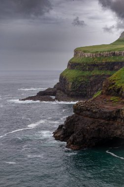 Dramatik Mulafossur şelalesi Gasadalur köyü ve arka planda kayalıklarla okyanusa dökülüyor..