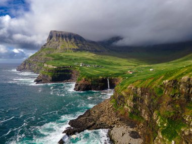 Dramatik Mulafossur şelalesi Gasadalur köyü ve arka planda kayalıklarla okyanusa dökülüyor..