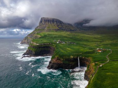 Dramatik Mulafossur şelalesi Gasadalur köyü ve arka planda kayalıklarla okyanusa dökülüyor..