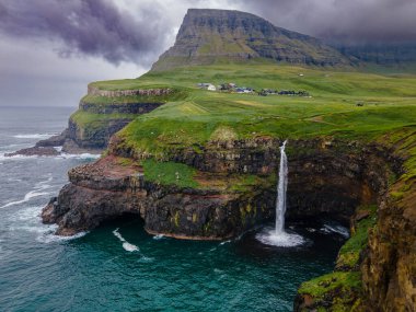 Dramatik Mulafossur şelalesi Gasadalur köyü ve arka planda kayalıklarla okyanusa dökülüyor..