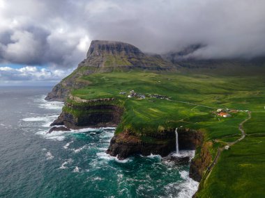 Dramatik Mulafossur şelalesi Gasadalur köyü ve arka planda kayalıklarla okyanusa dökülüyor..