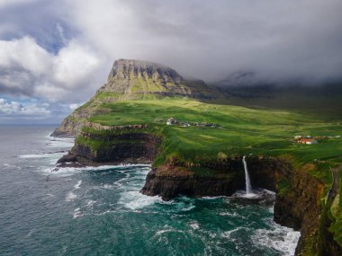 Dramatik Mulafossur şelalesi Gasadalur köyü ve arka planda kayalıklarla okyanusa dökülüyor..