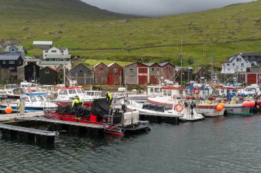 Liman boyunca Sorvagur feribot, tekne ve geleneksel balıkçı evlerinin manzarası..