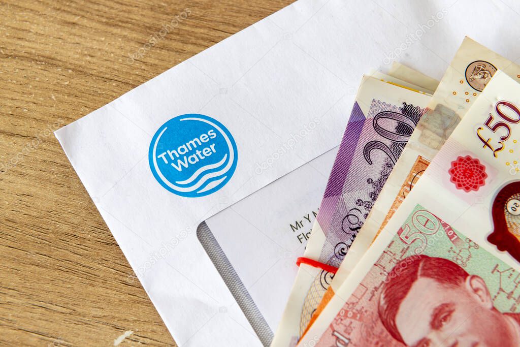 London. UK- August 31.2025. A macro close up of a Thames Water bill with a stack of Pound Sterling bank notes on top.