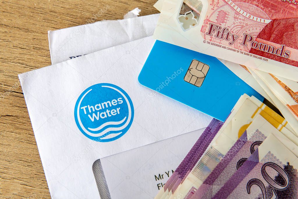 London. UK- August 31.2025. A macro close up of a Thames Water bill on top of another utility bill with a bank card and a stack of Pound Sterling bank notes on top. A cost of living concept.