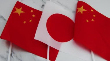 The national flag of Japan on flag pole in between the Chinese national flag. A Japan, China relations concept.