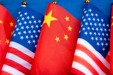 A row of USA and China national flags on flag pole with a blue background. A USA, China relations concept.