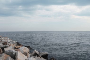 Sakin deniz kıyısında taşlarla. Bulutlu gökyüzü ve sakin deniz. Muhteşem bir doğa fotoğraf.