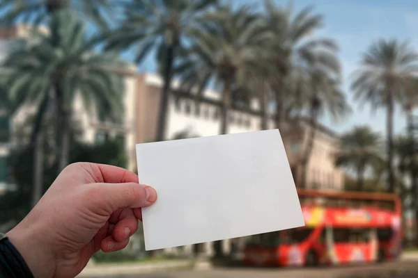 Vita vykort mockup i mans hand på bakgrunden palmerna och resor buss på Mallorca Island i Spanien. — Stockfoto