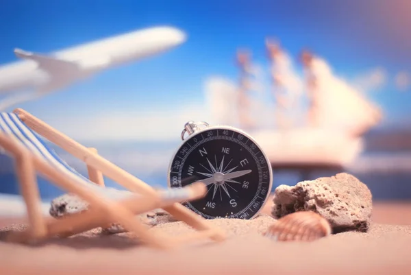 Time to Travel. Idea for tourism with compass and chaise lounge on the sand with corals on the background of the sea, ship and plane