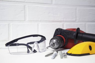 Sondaj için profesyonel bir araçtır. Bir tuğla duvar arka plan üzerinde koruyucu gözlük ile elektrikli matkap