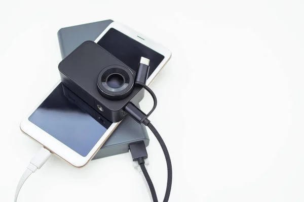 ポータブル充電ガジェット。白い背景にパワーバンクに接続されたアクションカメラ付きスマートフォン. — ストック写真