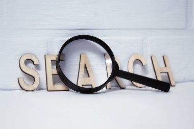 Kavram arama konu. Beyaz arka planda siyah kolu ve ahşap harfler ile Büyüteç.