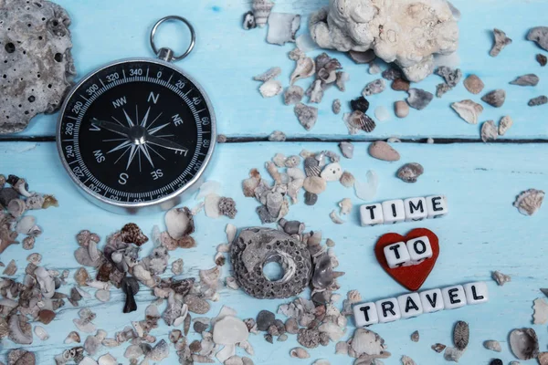 Ideje utazni. Ötlet a turizmus iránytű a homok korallok a fából készült háttér. — Stock Fotó