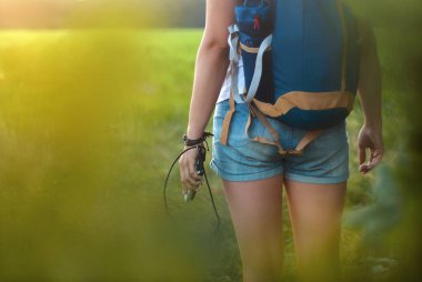 Sırt çantası olan bir kız. Turist elinde bir akıllı telefon ve orman ve yeşil alan arka planda bir Power Bank tutar.