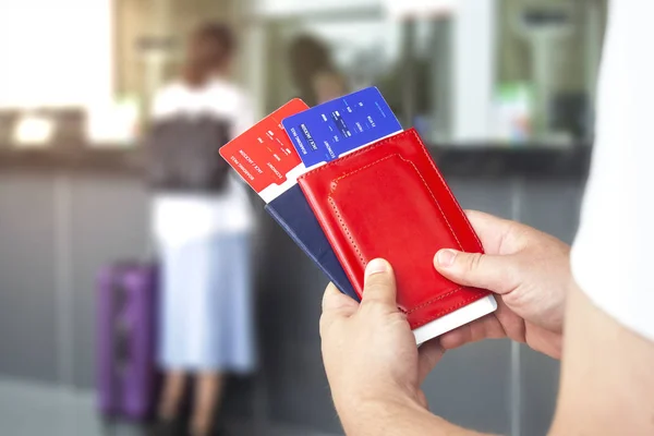 Egy ember kezében repülőjegy és útlevél. Turista a repülőtéren, a háttérben az utasok és a jegyirodai — Stock Fotó
