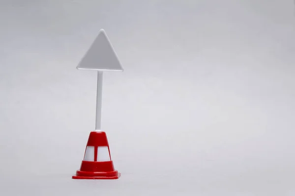 Makettet egy miniatűr háromszög útjelző jel egy világos háttér. — Stock Fotó