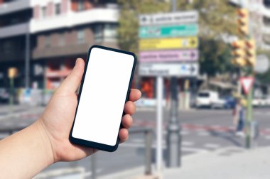 İnsan eliyle akıllı telefonun bir kopyası. Arka planda şehir binaları ve sokak işaretleri olan beyaz bir ekran var. Mobil navigasyon uygulaması için şablon