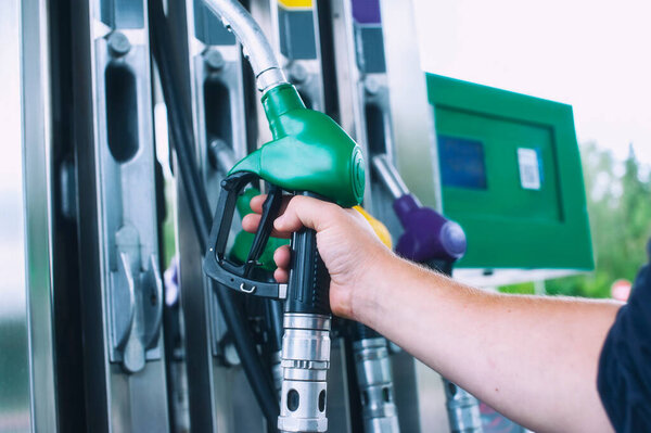 Man holds a refueling gun in his hand for refueling cars. Gas station with diesel and gasoline fuel close-up
