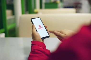 Video kanalına abone ol. Beyaz akıllı telefon ekranındaki eylem simgesini ara. Elinde telefon olan bir adam.