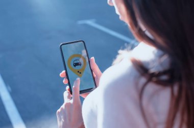 Otoparkta bir kız yolcu cep telefonu kullanıyor ve internetten taksi çağırıyor.