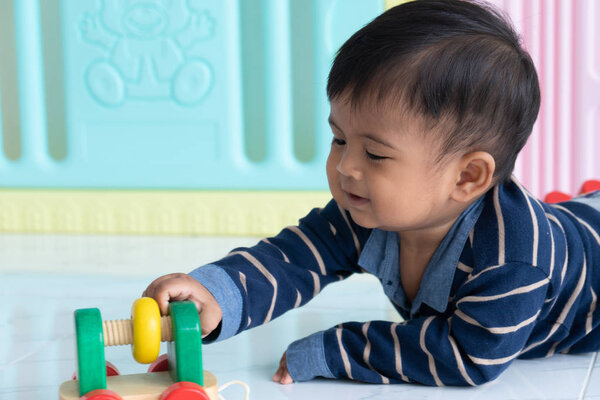 Милый счастливый маленький азиатский мальчик лежал играть деревянные игрушки автомобиль
