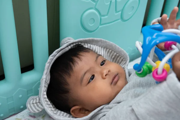 Bonito pouco asin bebê menino deitado no macio cobertor e jogar brinquedo — Fotografia de Stock