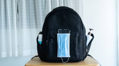 Okula geri dön, dezenfektan elli okul çantası, maske, alkol jeli, koronavirüs.