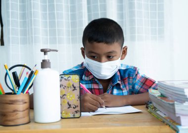 Küçük sevimli Asyalı çocuk evde akıllı telefonuyla internetten öğreniyor, Coronavirus.