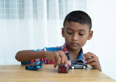 Küçük tatlı Asyalı çocuk odada oyuncak araba oynuyor.