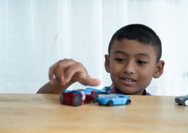 Küçük tatlı Asyalı çocuk odada oyuncak araba oynuyor.