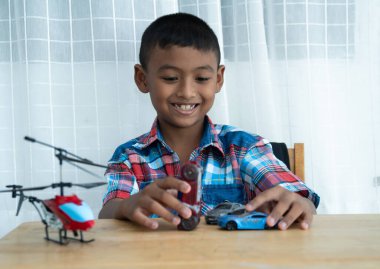 Küçük tatlı Asyalı çocuk odada oyuncak araba oynuyor.