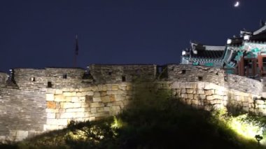 Hwaseong Kalesi 'nin sağında geceleyin Suwon, Güney Kore' de ay varken..