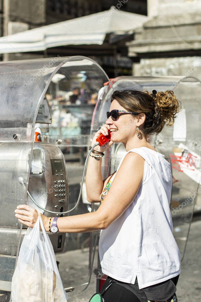 Woman using a telephone booth and laughing