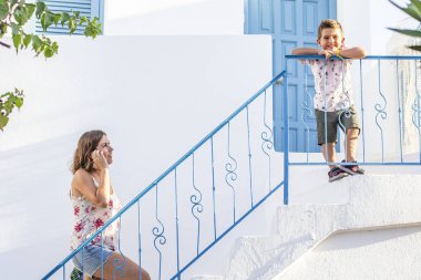 Anne ve oğlu mavi bir korkuluk ile beyaz bir merdiven üzerinde