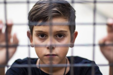 Çocuk bir kafes içinde kilitli. Mülteciler çatışma kavramı.