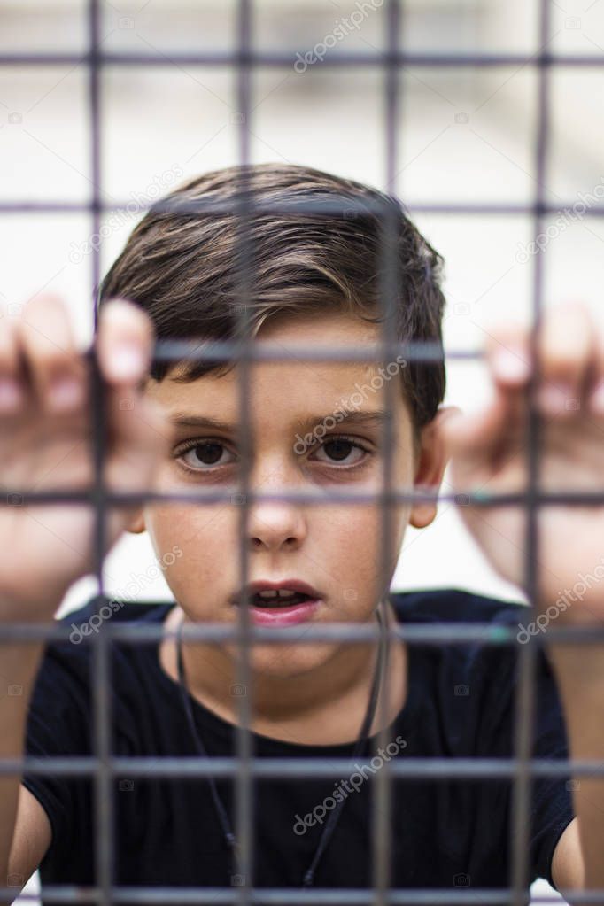 Child locked in a cage. Refugees conflict concept.