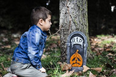 Küçük çocuk bir Cadılar Bayramı mezar ile ormanda