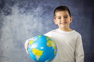 Küçük çocuk bir dünya top ile gülümseyen