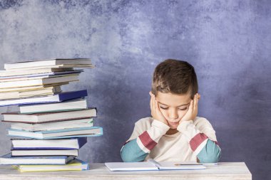 Küçük çocuk vurguladı bir kitap yığını ile ödev