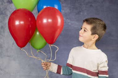 Bir sürü balon tutan tatlı bir çocuk.