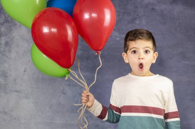 Bir sürü balon tutan tatlı bir çocuk.