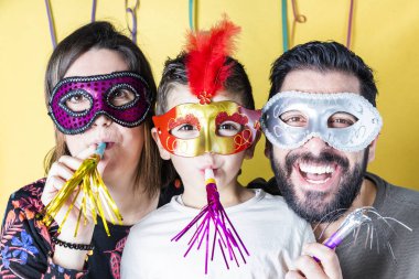 Karnaval sarı arka plana sahip maskeleriyle mutlu aile
