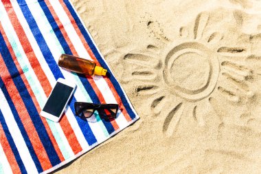 Plaj havlusu, cep telefonu ve sahilde güneş kremi