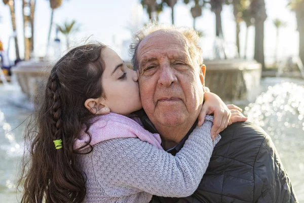 Девочка целует своего дедушку на улице — стоковое фото