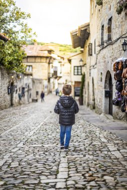 Lonely boy walking through the streets of an old  city clipart