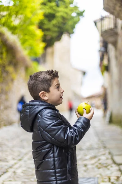 Bellissimo ragazzo mordere una mela per strada — Foto Stock