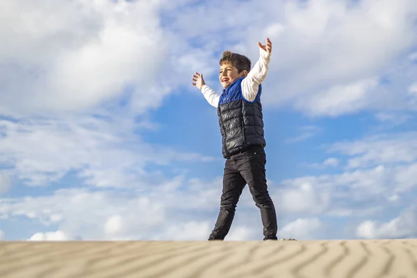 Niño pequeño con los brazos arriba de una duna — Foto de Stock
