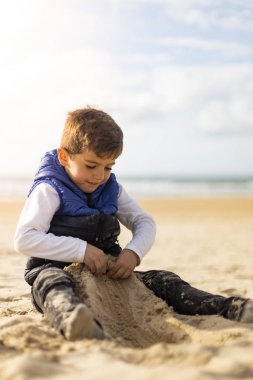 Bir plajın kumu ile oynayan güzel çocuk